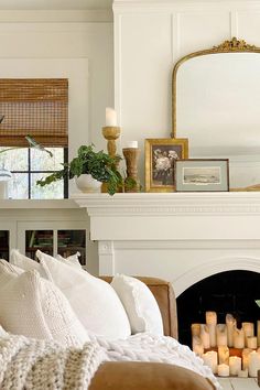 a living room filled with furniture and a fire place in front of a mantle topped with candles