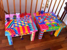 two brightly colored tables sitting on top of a wooden floor next to a stair case