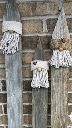 two gnomes made out of wooden boards on the side of a brick wall, one wearing a knitted hat