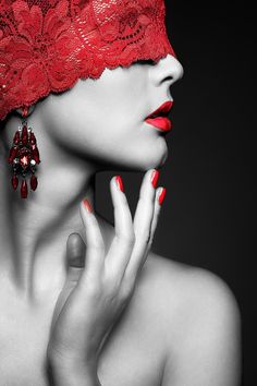 a woman with red nail polish wearing a red lace headdress and matching earrings