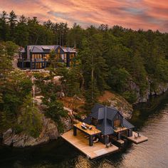 an aerial view of a house on the water with trees and rocks in the background