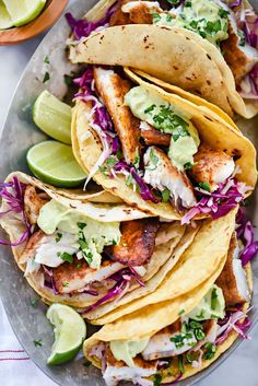 three fish tacos on a plate with lime and cilantro garnish