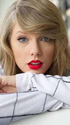 a close up of a person wearing a white shirt and red lipstick with her hand on her shoulder