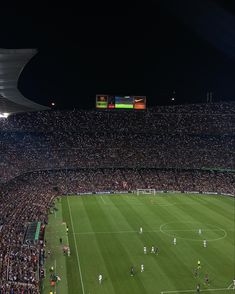 a soccer stadium filled with lots of people watching the game at night, as well as onlookers