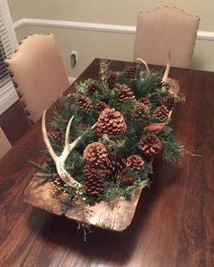 a wooden table topped with lots of pine cones and deer antlers on top of it