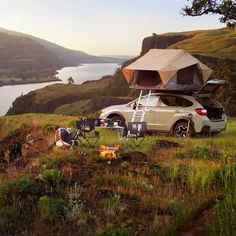 a car parked on top of a lush green hillside next to a body of water