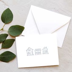 two houses are drawn on white paper next to green leaves and a card with the word home