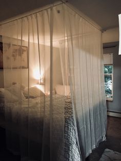 a canopy bed with sheer curtains over it