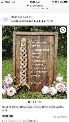 a wooden sign sitting in the grass next to some flowers and greenery on top of it