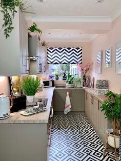 a kitchen with black and white tile flooring, potted plants and pictures on the wall