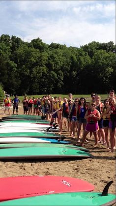 a group of people standing on top of a beach next to surfboards