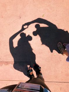 two people standing next to each other with their shadows on the ground