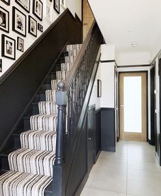 the stairs are lined with pictures on the wall and below them is a black iron handrail