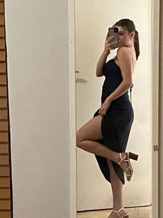 a woman taking a selfie in a mirror with her legs crossed and heels on