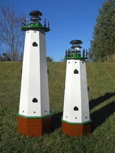 two white and green lighthouses sitting in the grass