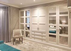 a bedroom with mirrored closet doors and a blue chair in the corner next to it