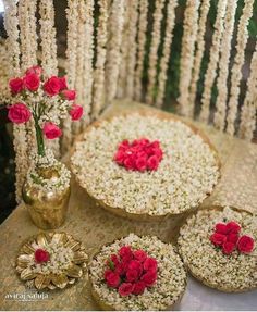 red flowers are placed on the table next to some round cakes and vases with white flowers in them