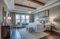 a bedroom with wood floors and white bedding in front of a large window on the wall