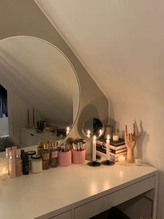 a vanity with candles, mirror and other items on it in a room that looks like an attic