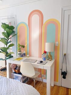 a white desk sitting in front of a colorful wall