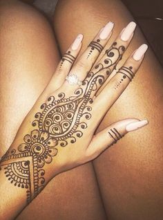 a woman's hands with henna tattoos on her arm and hand, showing the intricate design