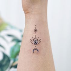 a woman's arm with an evil eye and star tattoo on the left side