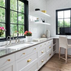 a kitchen with white cabinets and gold pulls on the handles, along with black framed windows