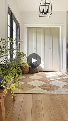 a living room with wooden floors and plants in the corner on either side of the door