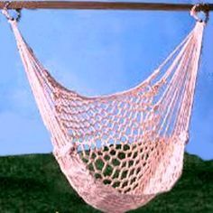 a pink hammock hanging from a wooden pole on the grass in front of a blue sky