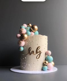 a white cake with gold, blue and pink decorations on it's side that says baby