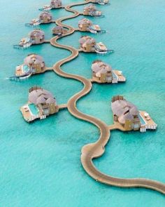 an aerial view of some houses in the water with a long road going through them