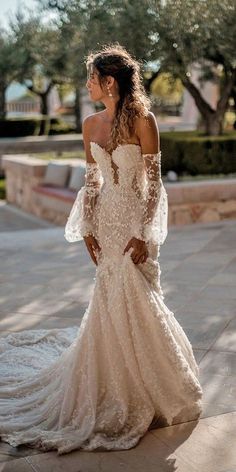 a woman in a wedding dress is standing on the sidewalk with her back to the camera