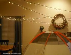 a room with lights strung from the ceiling and a tent in the foreground that has a wreath on it