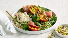 a salad with watermelon, peaches and mint on top is served in a white bowl