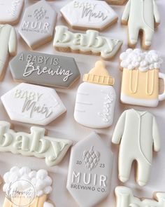 baby shower cookies are arranged on a white tablecloth with the names of babies, beer, and other items