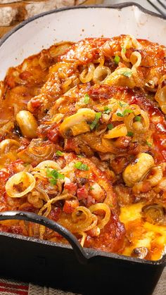 a skillet filled with pasta and meat covered in sauce