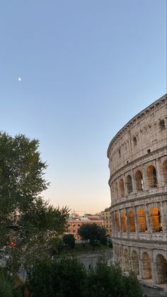 the roman colossion at dusk with a half moon in the sky