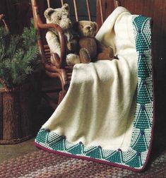 two teddy bears sitting in a rocking chair under a blanket on top of a rug