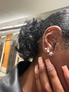 a close up of a person with ear piercings on their ears and hand near her face