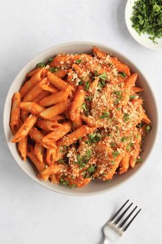 a white bowl filled with pasta covered in parmesan cheese and garnished with parsley