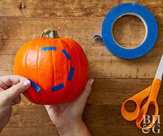 someone is carving a pumpkin with scissors and tape