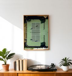 a record player is playing tennis on the wall next to a plant and bookshelf