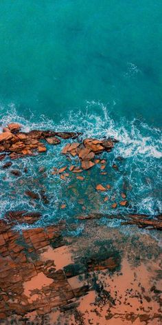 an aerial view of the ocean and rocks