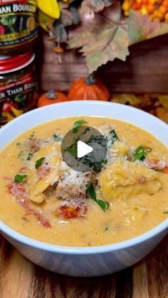 a white bowl filled with soup on top of a wooden table next to pumpkins