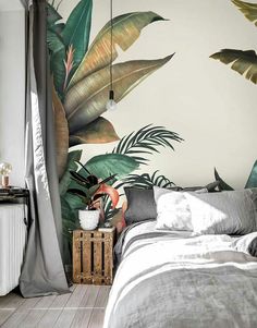 a bedroom decorated with tropical leaves on the wall