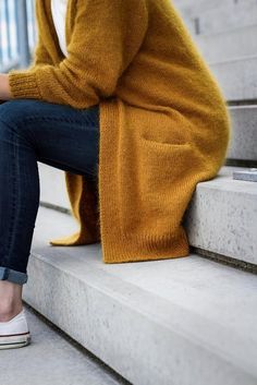 a woman sitting on the steps with her legs crossed and looking at her cell phone