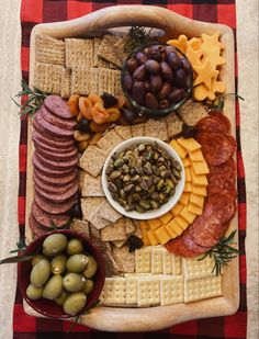 a platter filled with cheese, crackers, olives and meat