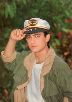 a young man wearing a sailor's hat while holding his hand to his forehead