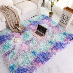 a living room with white couches and a rug on the floor that is covered in blue and purple colors