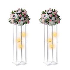 two tall clear vases with flowers and candles on the sides, one is filled with pink and white flowers